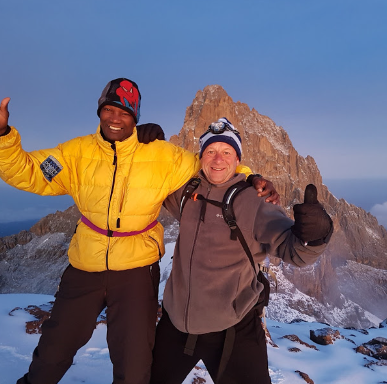 Tourist posing at Point Lenana on Mount Kenya after a hiking safari